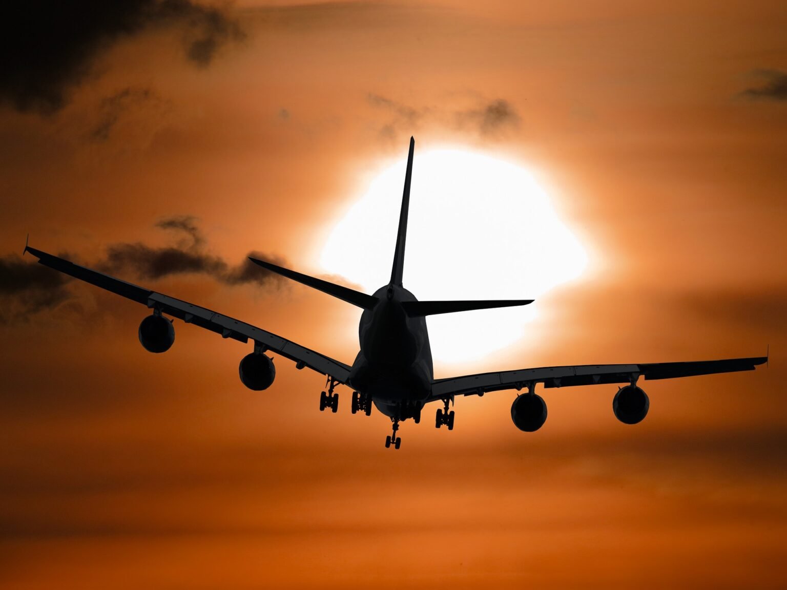 An aircraft in silhouette against a setting sun