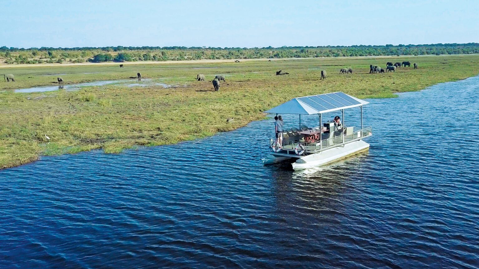 A small boat on the Chobe River with the floodplain beyond